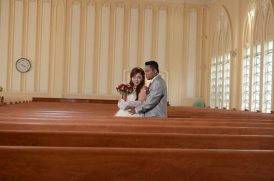 Bride and groom standing amidst benches in church