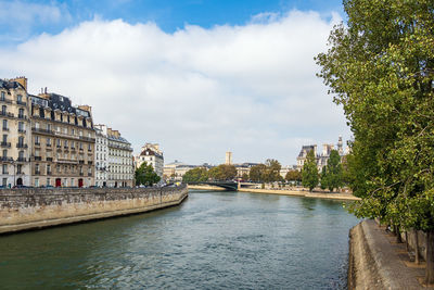 River by buildings in city against sky