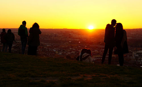 Silhouette people standing on land against sky during sunset