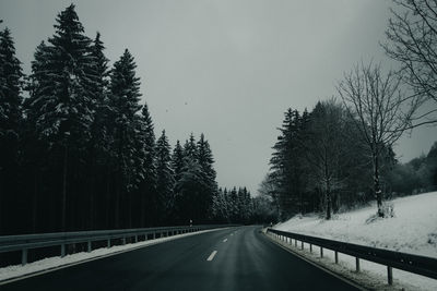 Road amidst trees against sky during winter