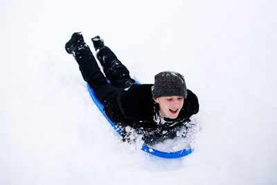 Full length of shirtless boy lying on snow