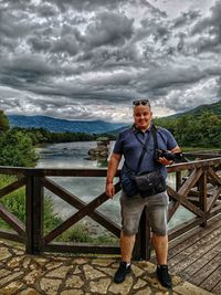 Full length of man standing on railing against sky