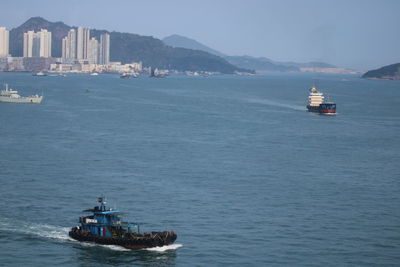 Ship sailing in sea against sky in city