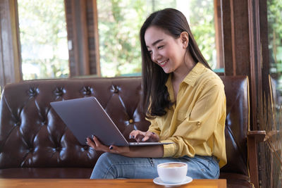 Young woman using mobile phone while sitting on table