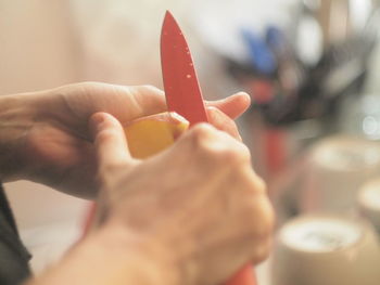 Close-up of human hand cutting potato