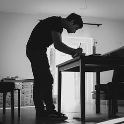 Side view of man working on table at home