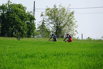 Rear view of people walking on field against clear sky