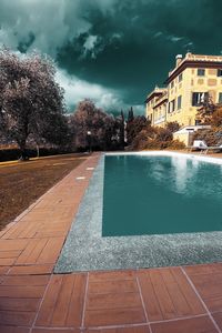 Footpath by swimming pool against buildings in city