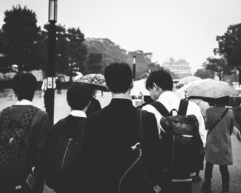 Rear view of people standing by tree in city