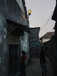 Rear view of man standing by old building against sky