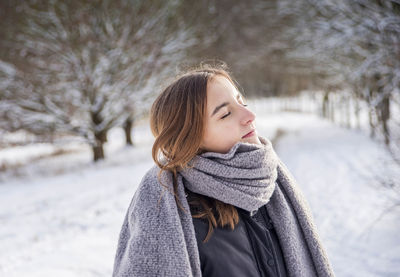 Portrait of woman on snow covered tree during winter