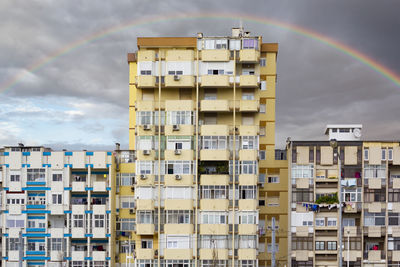 Low angle view of residential buildings against rainbow in sky