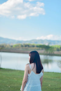 Rear view of woman standing against lake