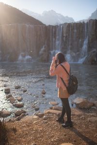 Rear view of woman standing at waterfall