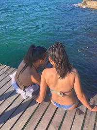 High angle view of friends sitting on pier by sea