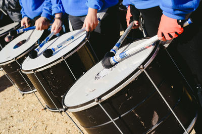 Midsection of men playing drums while standing outdoors