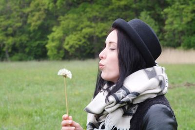 Portrait of woman holding flowers in field