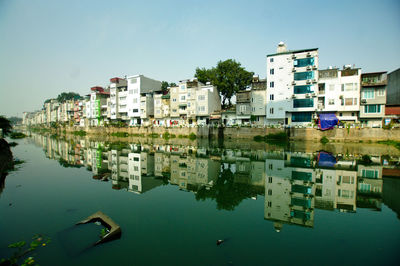 Buildings by lake against sky in city