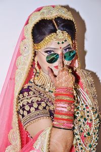 Portrait of bride in sari wearing sunglasses against wall