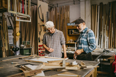 Senior craftsman discussing together while working at repair shop