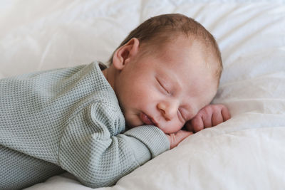 Cute baby boy sleeping on bed at home