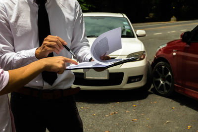 Owner pointing on paper with agent against cars