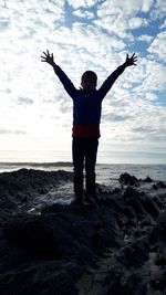 Full length rear view of man standing on rock at beach