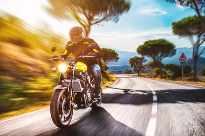 Man riding motorcycle on road against sky