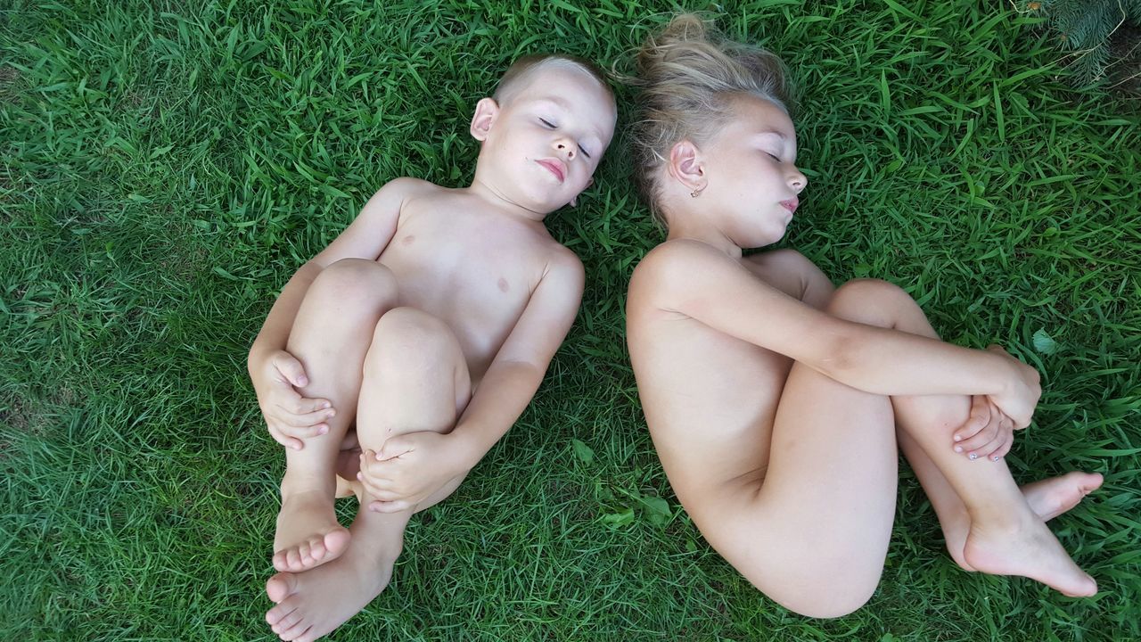 REAR VIEW OF YOUNG COUPLE ON GRASSY FIELD