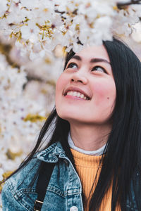 Smiling young woman looking at blooming flowers