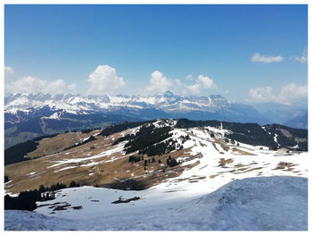 Scenic view of snow covered mountains against blue sky