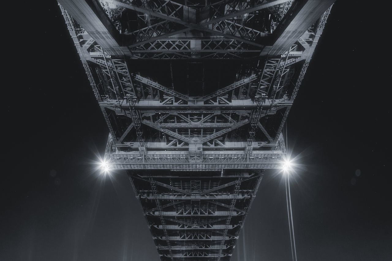 illuminated, architecture, low angle view, built structure, night, sky, no people, bridge - man made structure, lens flare, lighting equipment, travel destinations, bridge, connection, tower, light beam, tall - high, tourism, city, nature, travel, light, skyscraper
