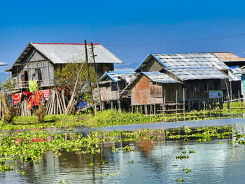 Houses by lake against buildings against clear sky