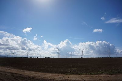 Windmills on field against sky