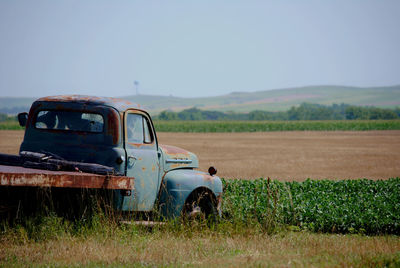 Abandoned old farm pickup truck on field against clear sky