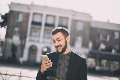 Young man using mobile phone in city