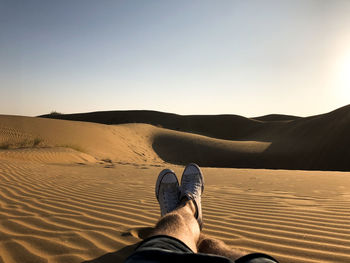 Low section of man standing on sand dune