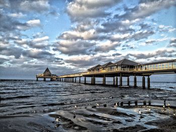 Pier on sea against cloudy sky