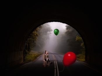 Man with balloons in tunnel