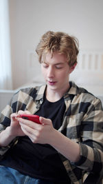 Young man using mobile phone while sitting at home