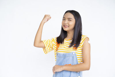 Portrait of smiling young woman standing against white background