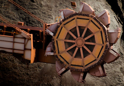 Close-up of bucket wheel against sand at industry