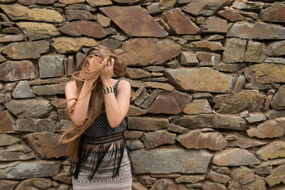 Woman standing by stone wall