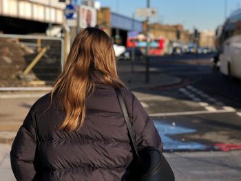 Rear view of woman with umbrella in city