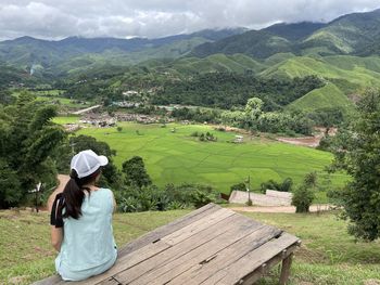 Rear view of woman sitting on mountain