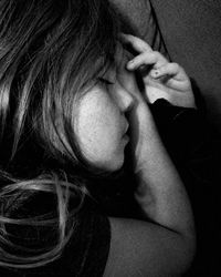 Close-up portrait of young woman with hair over black background