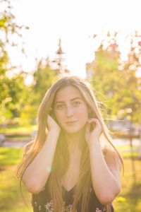 Portrait of young woman standing against plants