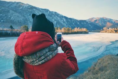 Rear view of person looking at lake during winter