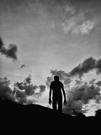 Rear view of silhouette man standing on field against sky