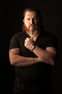 Portrait of man standing against black background